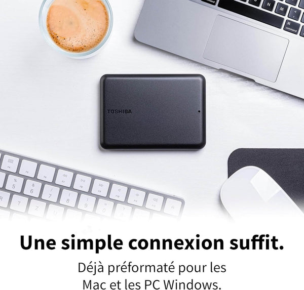 Disque dur portable Toshiba Canvio Partner 2 To posé sur un bureau à côté d’un clavier et d’une tasse.